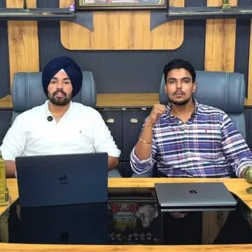 Two members of the HIR Dispatch team at the academy desk with laptops